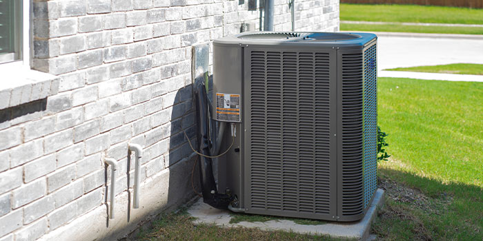 Outdoor air conditioning unit next to a brick house wall.
