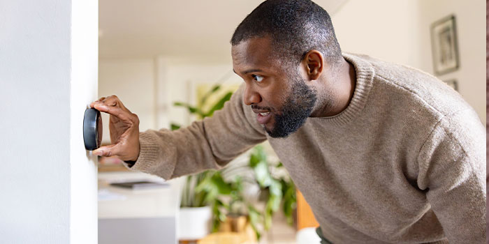 A man adjusting a smart thermostat in a modern home.