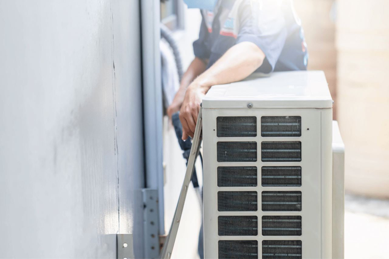 Technician working on outdoor air conditioning unit in sunlight.