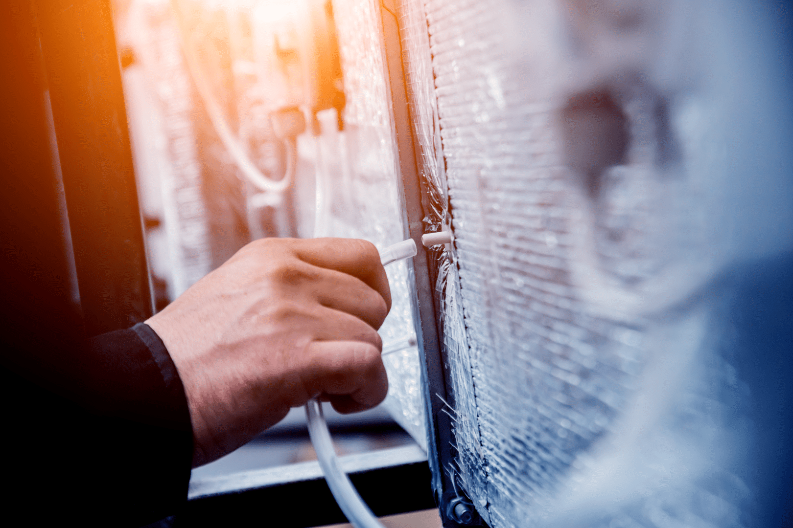 A hand connecting a cable to electronic equipment in a server room.