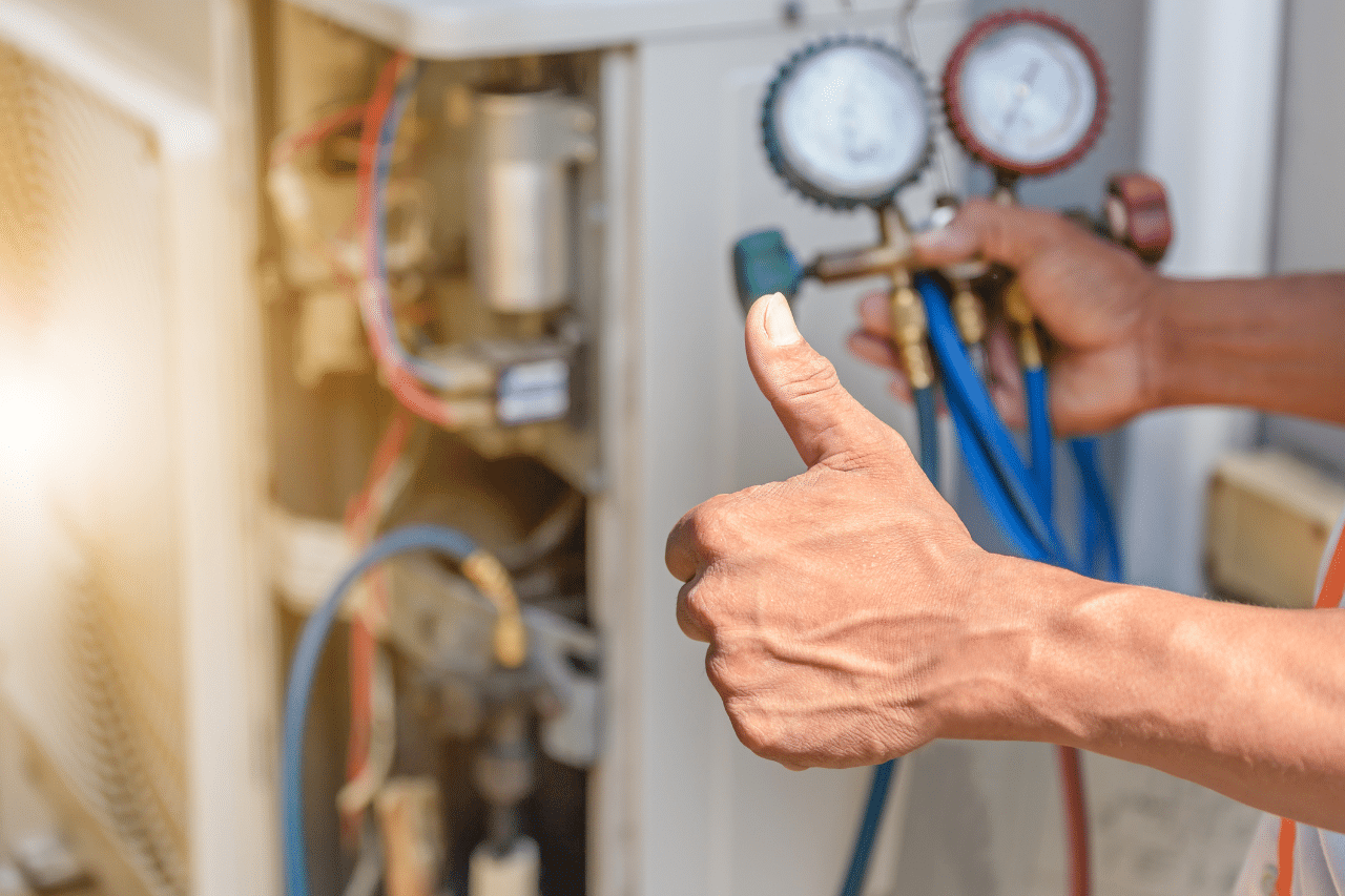Person giving a thumbs up while inspecting HVAC gauges.