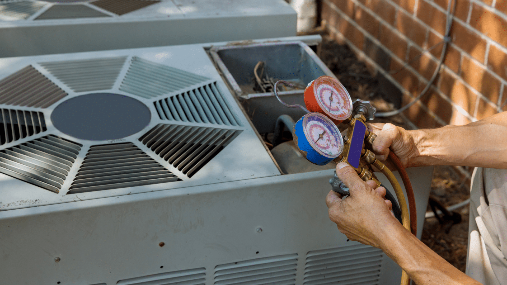 Technician adjusting AC unit with pressure gauges outside.