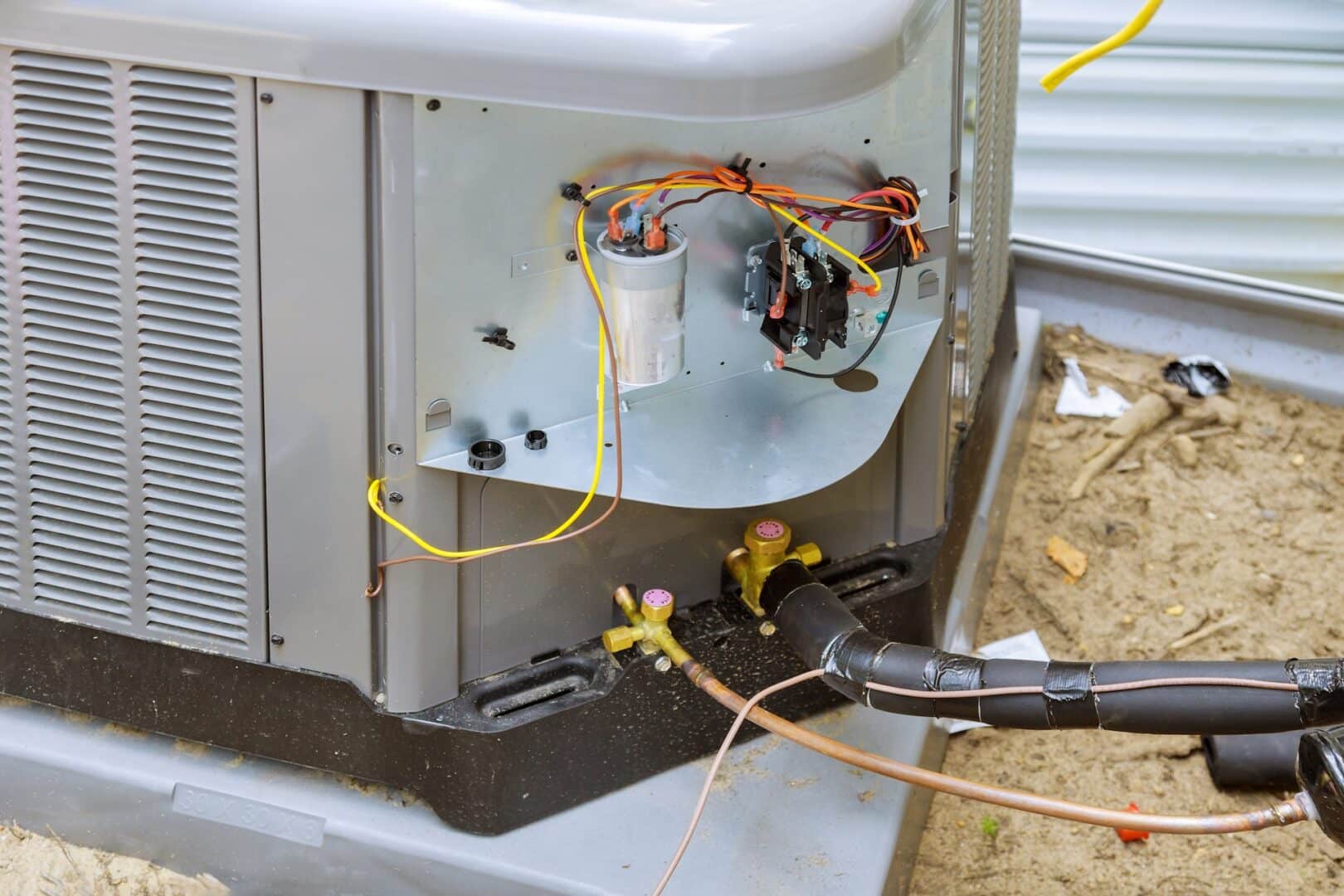 Air conditioning unit wiring and components outside a building.