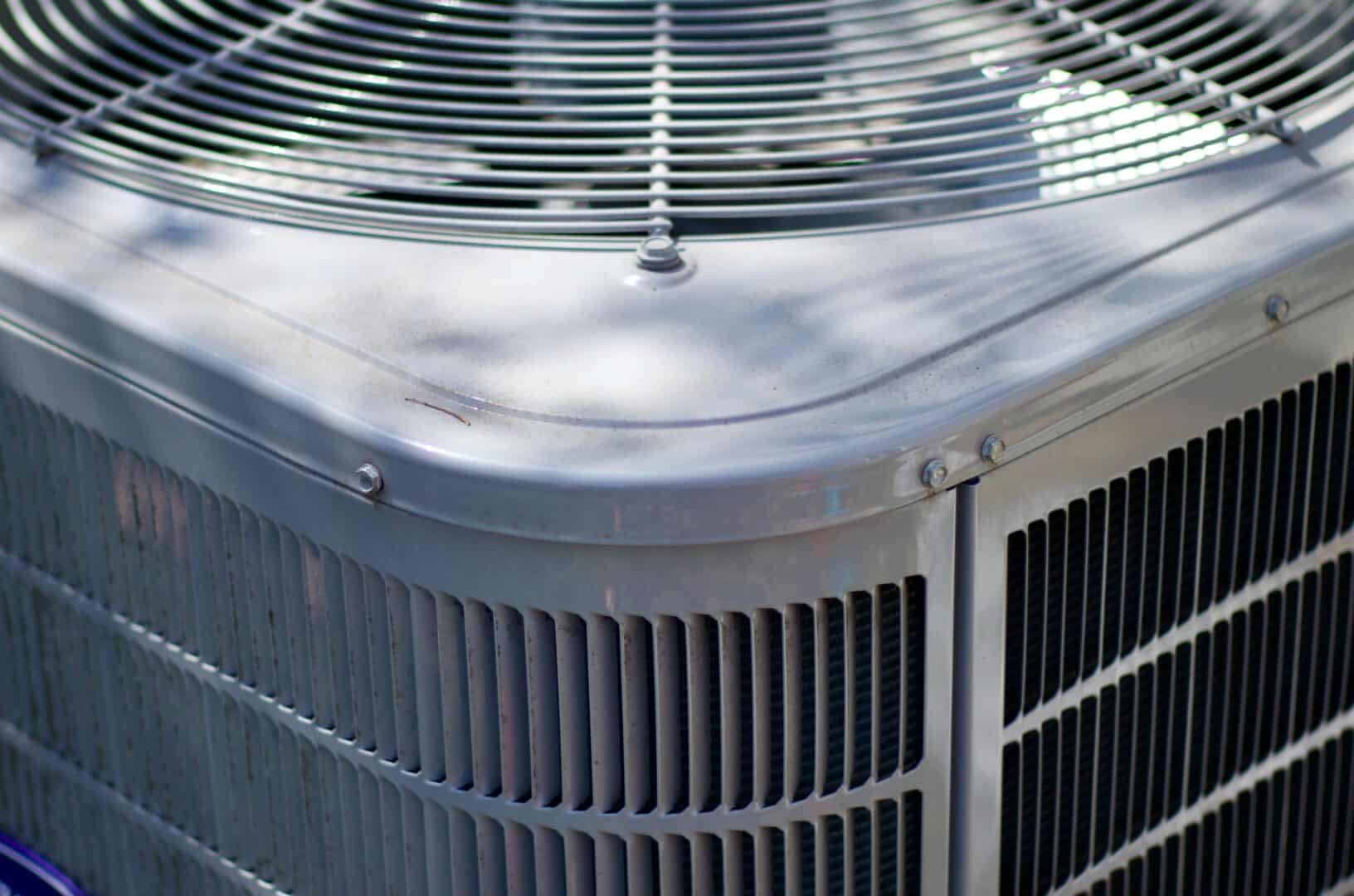 Close-up of an outdoor air conditioning unit with metal grille and fins.