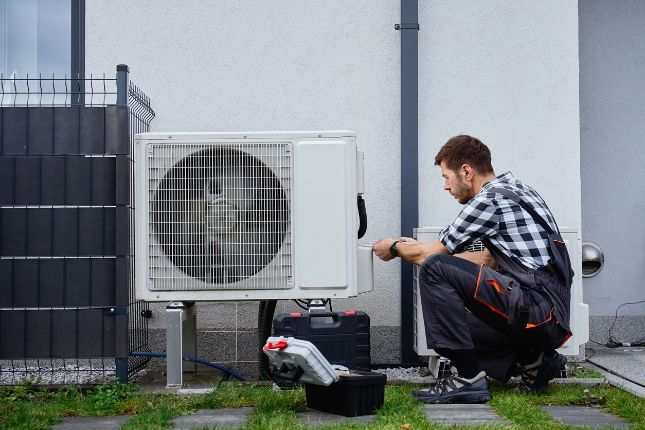 A technician services an outdoor heat pump unit, performing energy-efficient HVAC maintenance on a Tennessee home.